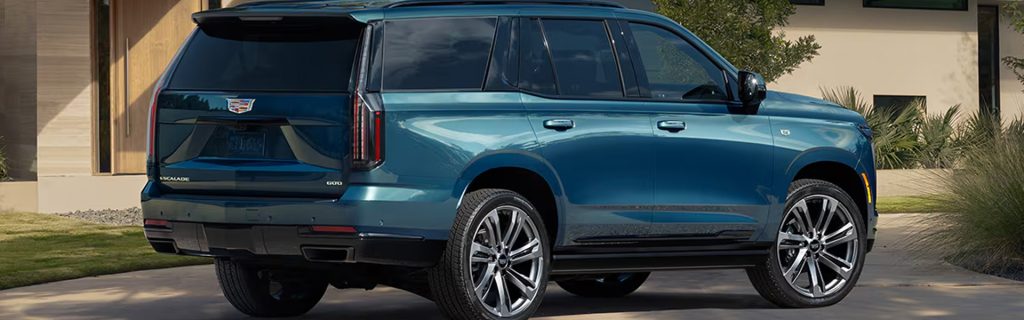 Blue Cadillac Escalade SUV parked outside a home.