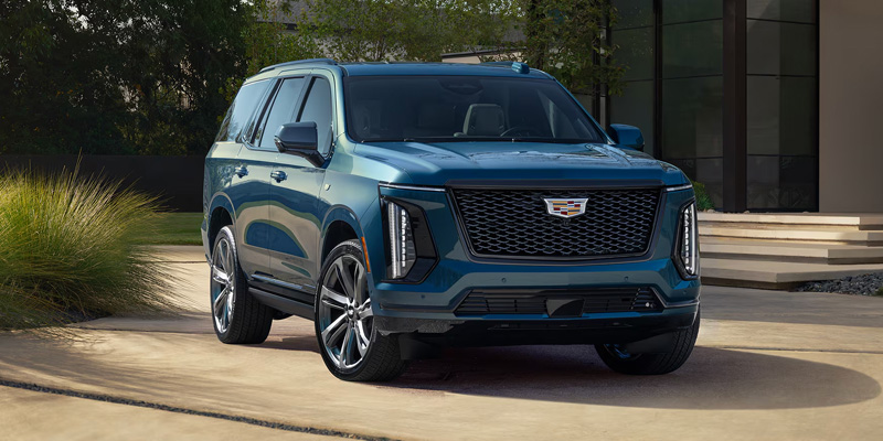 Blue Cadillac SUV parked outside a modern building with a luxury design