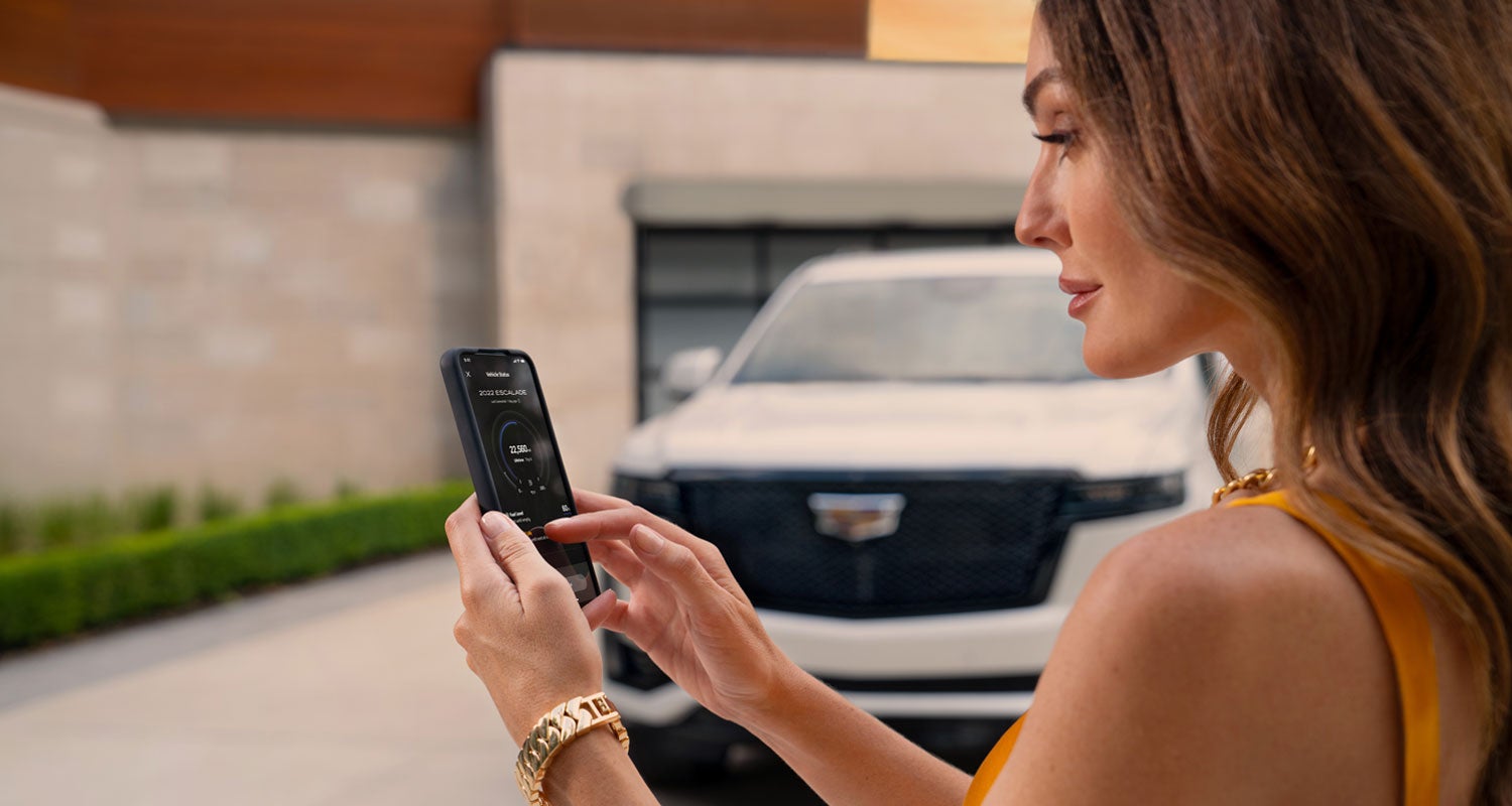lady checking her mobile with a Cadillac vehicle background | Medina Cadillac in MEDINA OH