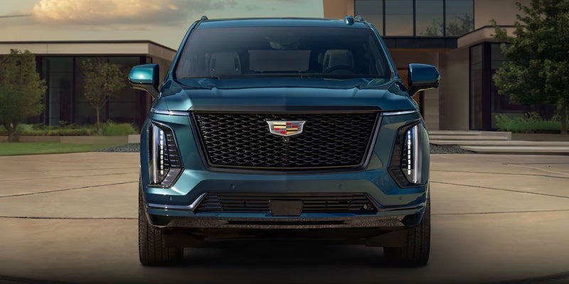 Front view of a blue Cadillac XT6 outside a modern building.